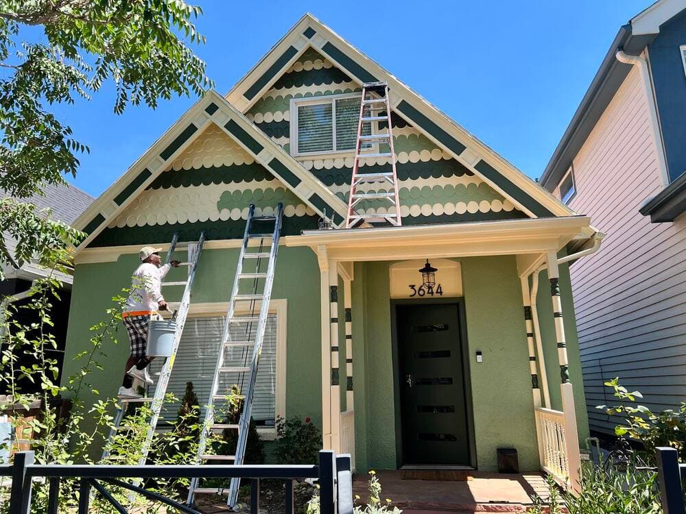 Elmwood painter on a ladder cutting in exterior trim